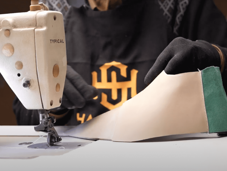 An artisan meticulously stitching leather components for shoe uppers.