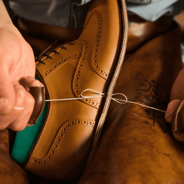 Skilled artisans crafting Handsole custom bespoke handmade leather shoes with meticulous detail.